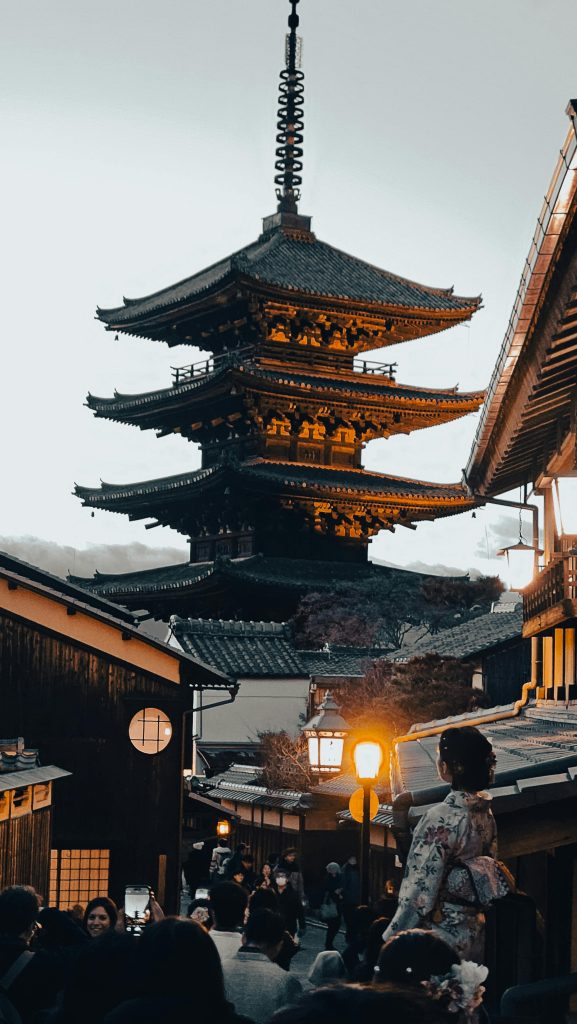 Captivating view of a traditional pagoda in Kyoto, Japan at twilight with people in kimonos walking nearby.